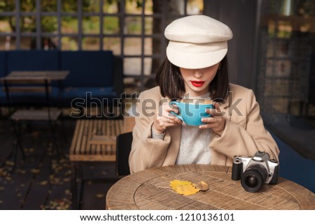 Mysterious woman in a hat is drinking coffee Royalty-Free Stock Photo #1210136101