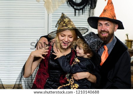 Happy family preparing for Halloween. Children wearing black and orange witch costumes with hats playing with pumpkin and spider in Halloween. Kids trick or treat.