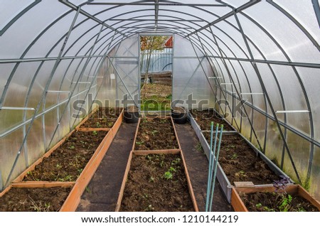 Empty beds inside a greenhouse made of polycarbonate in the fall Royalty-Free Stock Photo #1210144219