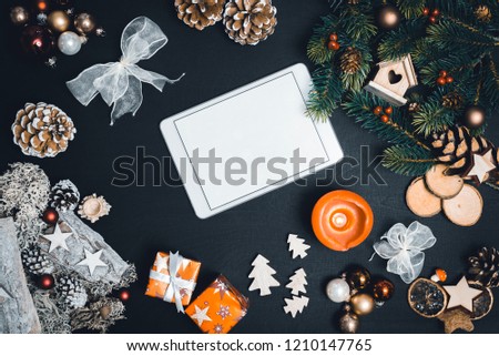 Christmas decoration and white tablet with copy space for happy new year message against black background as flatlay