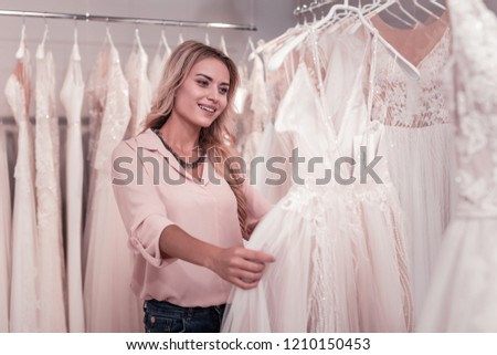 Beautiful bride. Cheerful young woman smiling while choosing a wedding dress