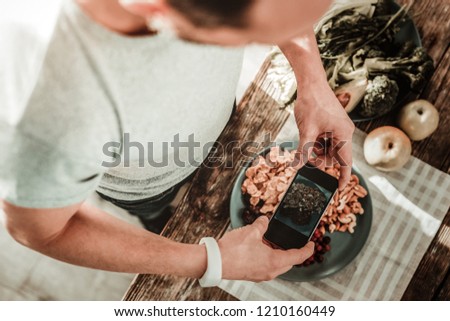 Beautiful picture. Nice smart man holding his smartphone while taking a photo of food