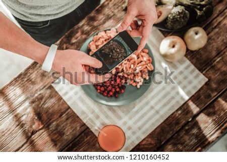 Pictures of food. Top view of a smartphone being in male hands while taking photos of food