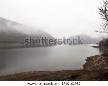 melancholic and solitary image of the lake of turano in autumn, immersed in the morning mist