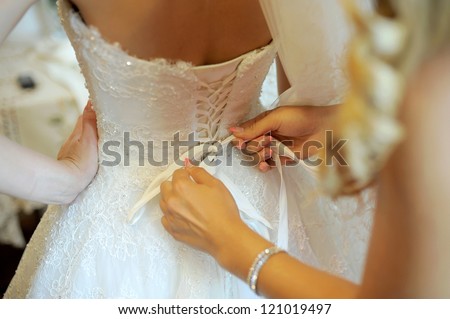 bridesmaid tying bow on wedding dress Royalty-Free Stock Photo #121019497