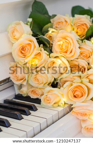 Peach roses with garlands on a white piano