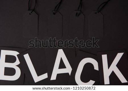 top view of blank price tags and black lettering on black surface, black friday concept