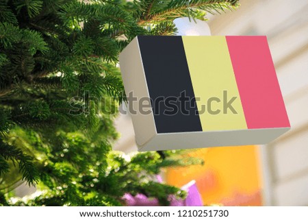 Belgium flag printed on a Christmas gift box. Printed present box decorations on a Xmas tree branch. Christmas shopping in Belgium, sale and deals concept. 