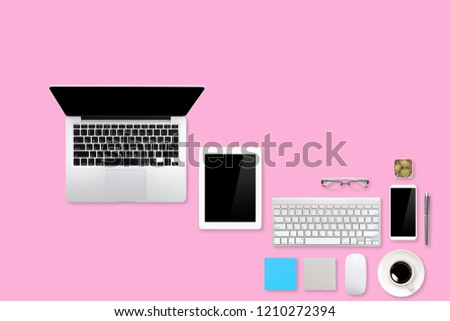 modern workspace table top view with laptop computer, coffee cup, office supplies, tablet and mobile on pink pastel background