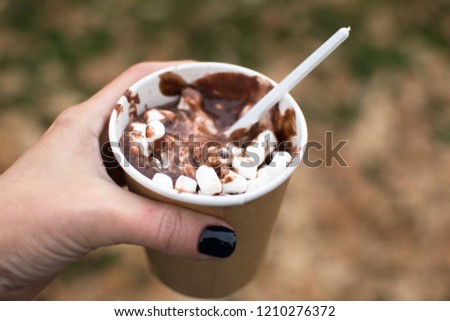 hot chocolate with marshmallows in a paper cup in a woman's hand