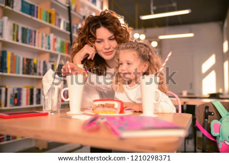 Playful mood. Petty curly haired female expressing positivity while embracing her daughter