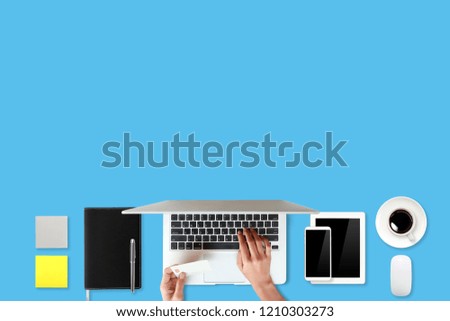 technology working table with woman hand on laptop computer, credit card, coffee cup and cell phone on blue background (or shopping and payment online concept)