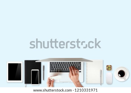 technology working table with woman hands on laptop computer, credit card, coffee cup and cell phone on blue background (or shopping and payment online concept)