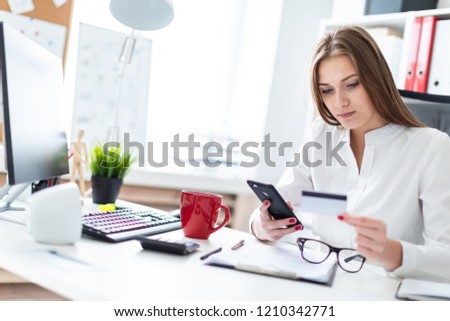 Slender young girl working in a bright office. Young girl in white blouse and black trousers. She has long brown hair. Girl with glasses and beautiful makeup. photo with depth of field