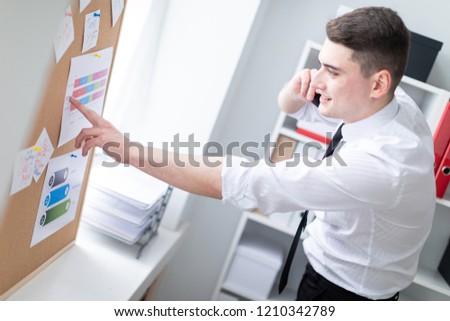Charming young man working in a bright office. Young man in white shirt with black tie and black trousers. photo with depth of field