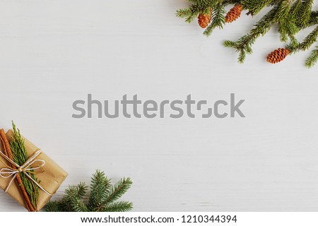 Christmas tree, gift and cones on a white wooden table. Preparation for writing the text, copy space.