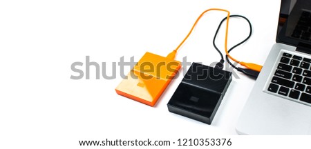 Close up of orange external hard disk drive for connect to laptop, transfer or backup data between computer and HDD. Black hard disc for backup files and important information using USB 3.0 connection