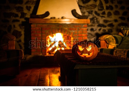 Creepy Halloween pumpkin near a fireplace. Fire on the background. Horror holiday concept