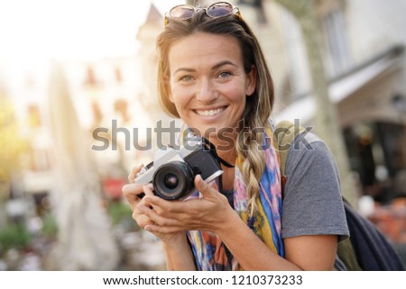 Attractive young woman taking photographs on SLR                              