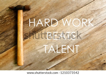 Inspirational and motivational quotes.Hard work beats talent. Hammer on wooden background.