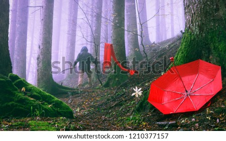 Murder following the victim in misty forest - Fiction scene of a homicide at spooky woods - Focus on red female umbrella fallen to the ground - Horror concept of femicide and violence on women