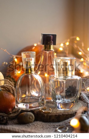 bottle of woman perfume  with pumpkins, ribbon, lights on knitted background. 
