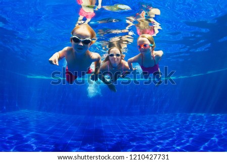 Happy family - mother, baby son, daughter in goggles swim, dive in pool with fun - jump deep down underwater. Healthy lifestyle, people water sport activity, swimming lessons on holidays with kids Royalty-Free Stock Photo #1210427731