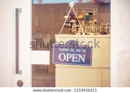 Open sign board through the glass of coffee shop door. Business service and food concept. Vintage tone filter color style.
