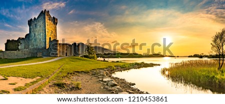 Panorama of ancient Ross Castle ruins with grass during sunset golden orange sky hour nobody Royalty-Free Stock Photo #1210453861