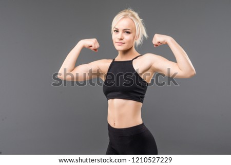 Young sporty woman looking at her biceps