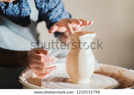 Potter creates jug nose, works on details and functionality of the product. Male artist operates hands, which gently creating correctly shaped handmade from clay