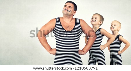  Family of strongman. The father of two sons in vintage costume of athletes perform strength exercises. Family look. Royalty-Free Stock Photo #1210583791
