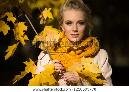 Pretty blonde girl in yellow autumn leaves