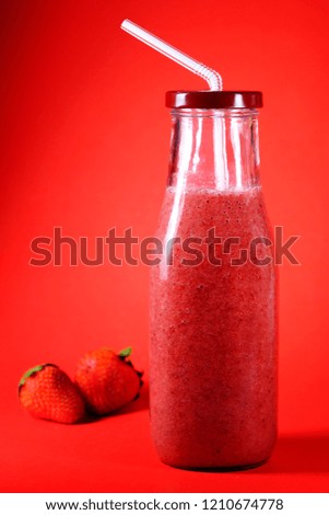Healthy strawberry smoothie bottle. Vegan drink on the red background. Delicious summer, vegan drink.