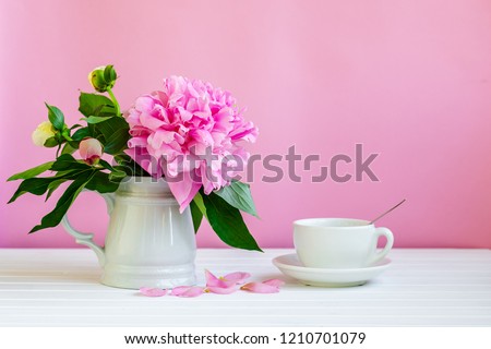 Pink peony next to glass of pink wine. pink background