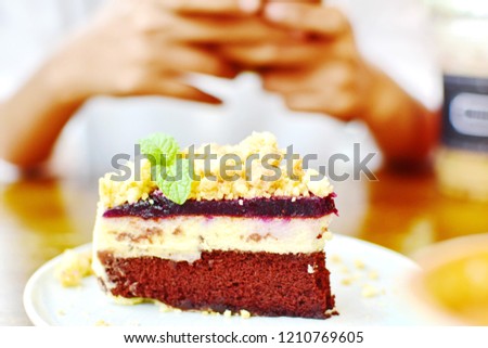 Shooting photo blueberry cheese velvet pie cake by smartphone, blurry of hand holding mobile and focus at delicious beautiful dessert, blogger or trend of social network shoot food before eat concept