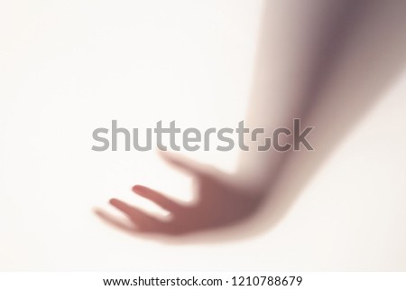 The concept of the shadow of hand behind frosted glass illuminated from behind.