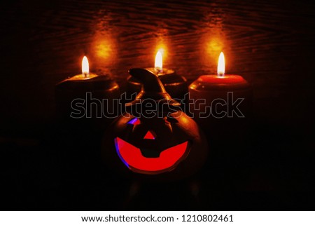 Halloween pumpkin with scary face and candles on black background