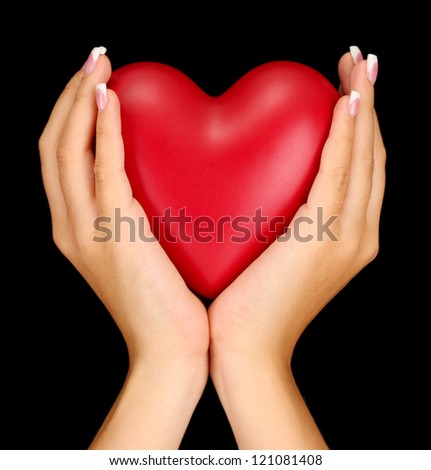 Red heart in woman's hands, on black background close-up