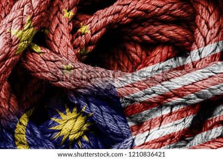 Country flags of China and Malaysia in a rope shape. Concept of foreign or diplomatic relations between countries.