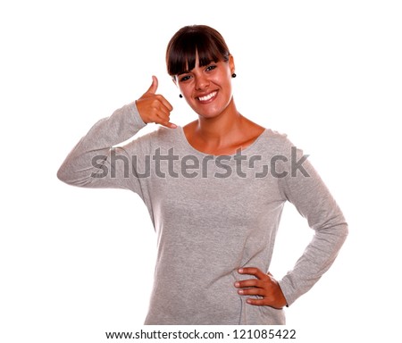 Portrait of a smiling young female saying call me with her hand on grey dress standing on isolated background