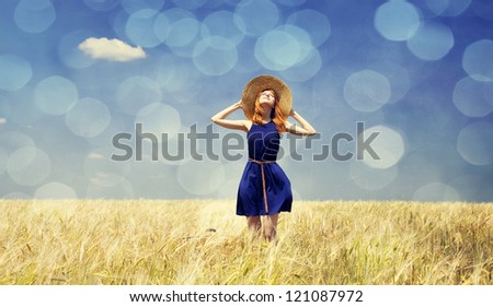 Redhead girl at spring wheat field.  Photo with bokeh at background.