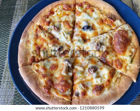 Top view of delicious hot Italian pizza in vegetarian style serve on blue plate. Fresh homemade mushroom thin crispy pizza crust with melting cheese is healthy vegetarian pizza in Italian recipe.   