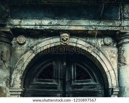 Old crypt entrance with death signs. Dark gate halloween, gothic effect of a crypt. Skull sign above  old wooden gate Royalty-Free Stock Photo #1210897567