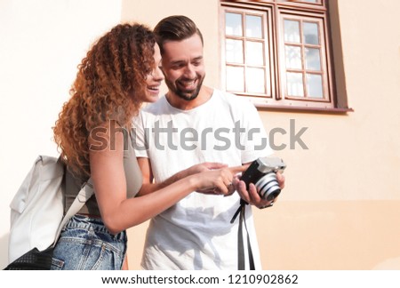 Portrait of young friends walking looking at the photos