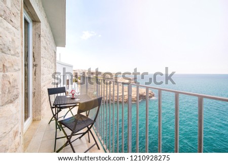 Braided modern garden furniture set on a sea side cliff balcony with a view of the horizon. Ships and yachts sailing in the background
