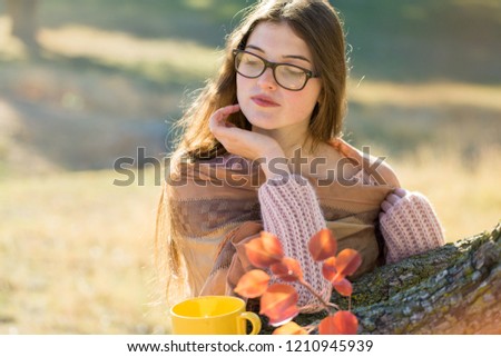 Portrait of pretty young woman in stylish knitted sweater standing on the golden autumn forest on sunny day