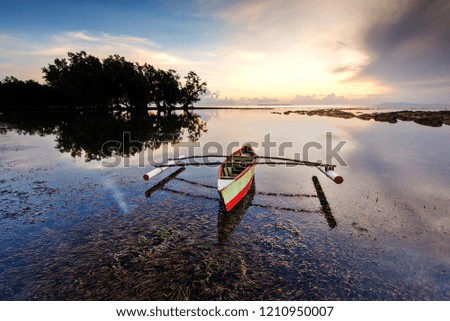 Sunrise at Tip Of Borneo, Malaysia with Reflection and sea grass. Beautiful local traditional fishing boat on the image.