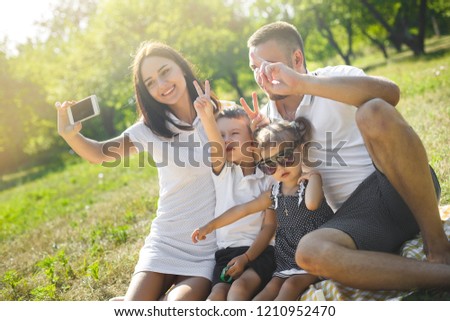 Cheerful family making selfie. Parents having fun with their kids outdoors. Cute family having picnic.