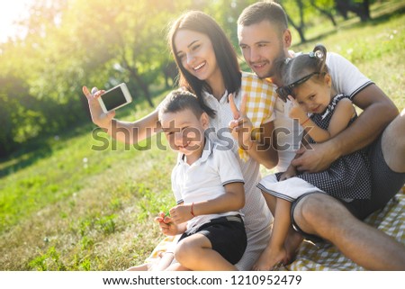 Cheerful family making selfie. Parents having fun with their kids outdoors. Cute family having picnic.